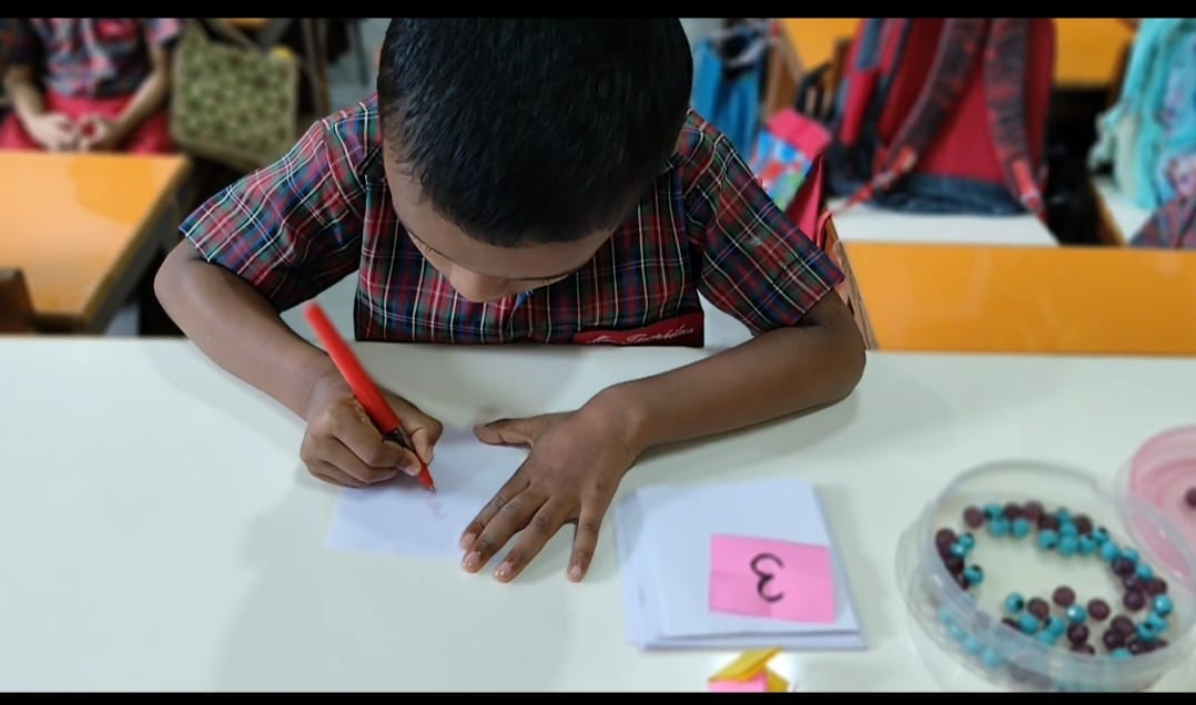 Child writing counted number on sheet card