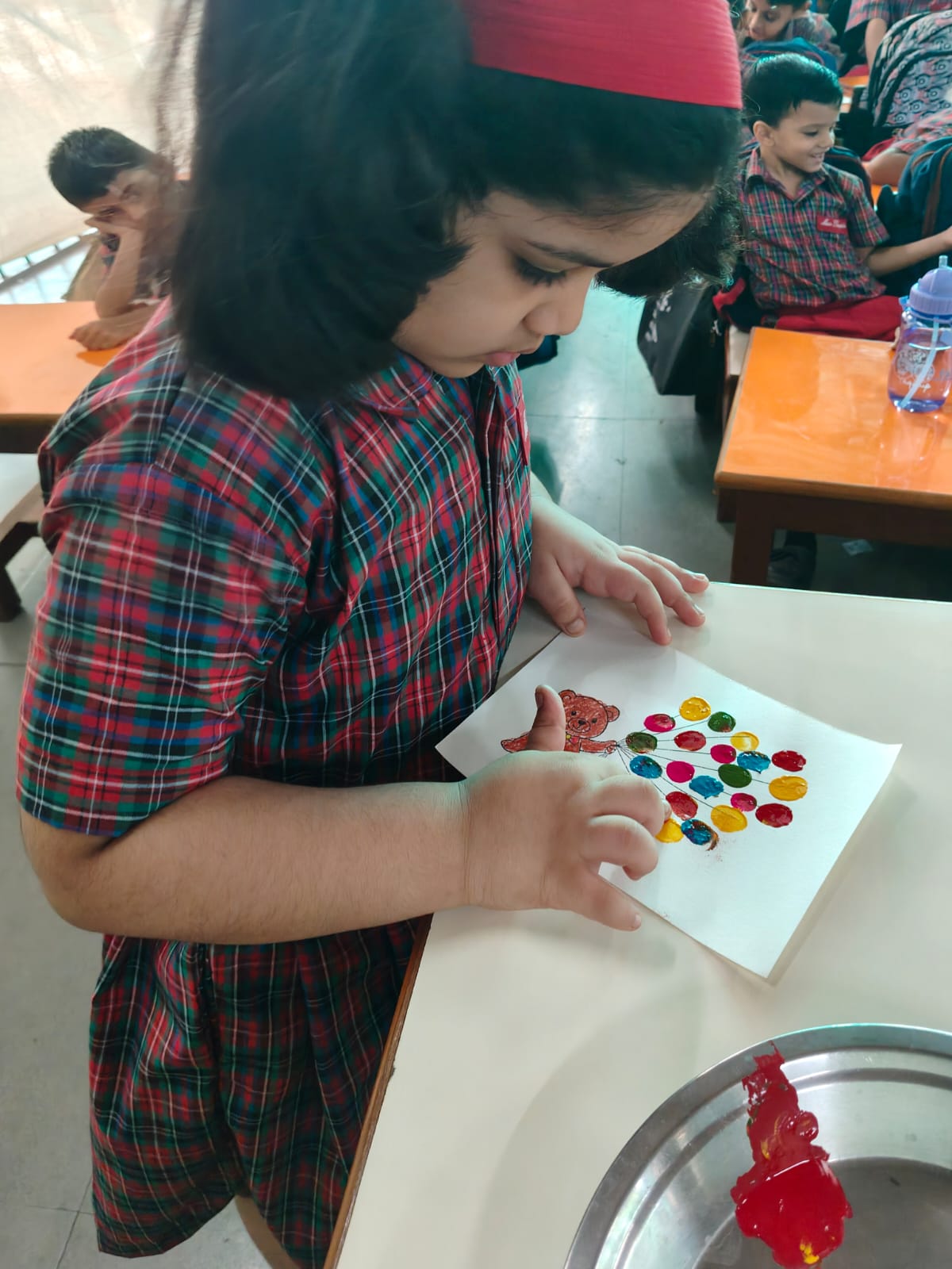 UKG - Child adding colorful fingerprint balloons to teddy sheet