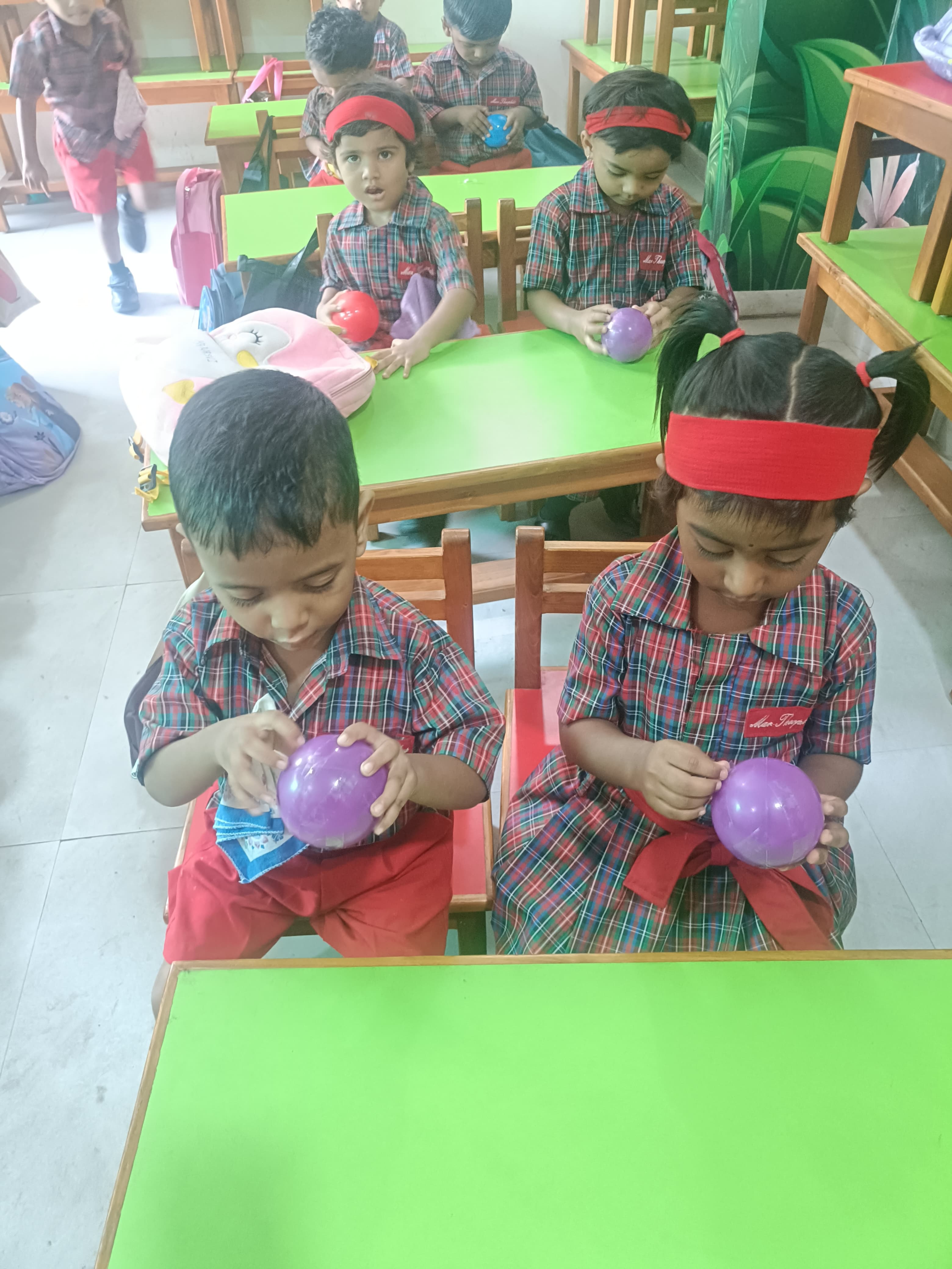 Classroom students wrapping tape layers around balls